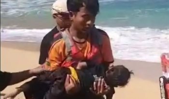 Petugas sedang menggendong balita yang terseret ombak di Pantai Drini
