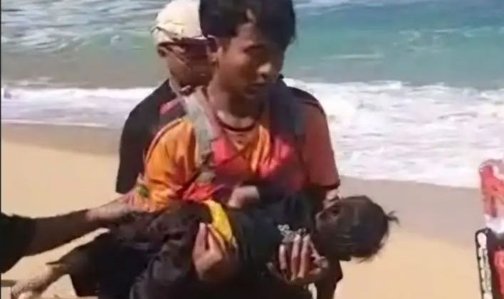 Petugas sedang menggendong balita yang terseret ombak di Pantai Drini